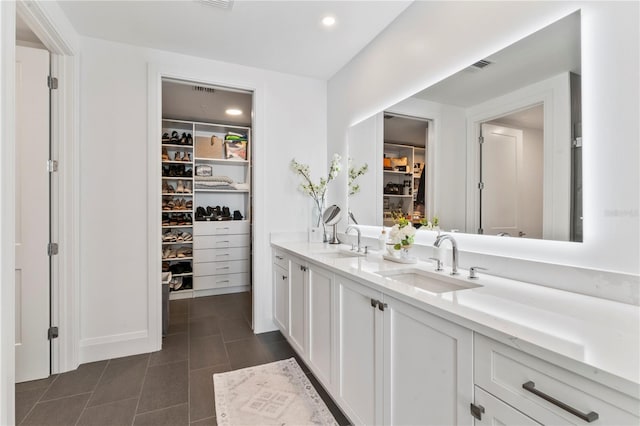 bathroom with a spacious closet, double vanity, visible vents, and a sink