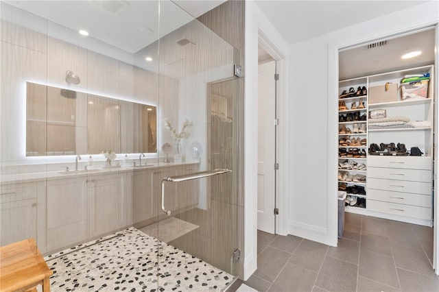 full bath with tile patterned floors, vanity, a walk in closet, and a stall shower