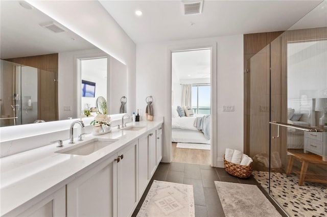 ensuite bathroom with visible vents, a stall shower, a sink, and connected bathroom