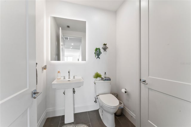 half bathroom featuring baseboards, tile patterned floors, toilet, visible vents, and a sink