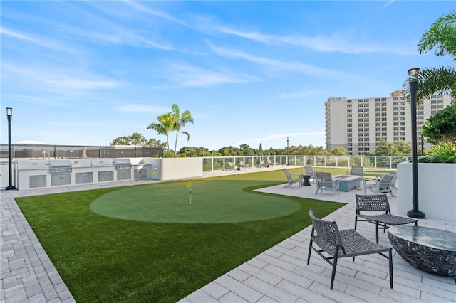 view of community with an outdoor fire pit, a patio, an outdoor kitchen, and fence