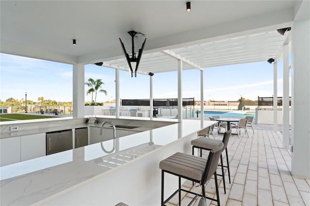 view of patio with an outdoor kitchen, a pergola, outdoor wet bar, fence, and a fenced in pool