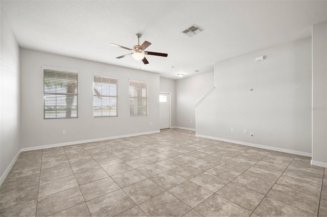 empty room featuring visible vents, a ceiling fan, plenty of natural light, and light tile patterned floors