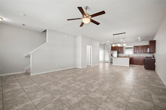 unfurnished living room with ceiling fan, visible vents, stairway, light tile patterned flooring, and baseboards
