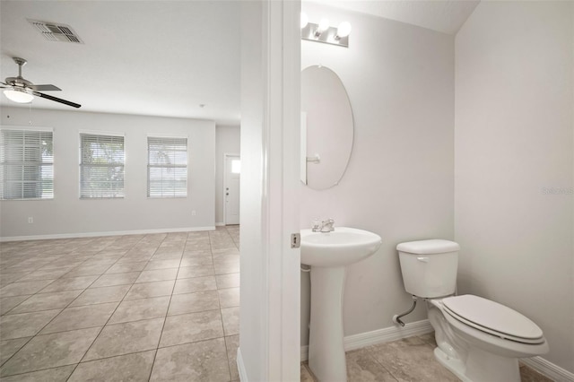 half bath featuring tile patterned flooring, toilet, visible vents, ceiling fan, and a sink