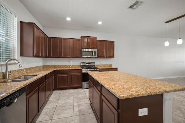 kitchen with a center island, light stone countertops, visible vents, appliances with stainless steel finishes, and a sink