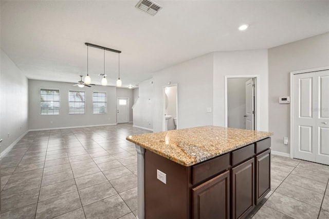 kitchen featuring light tile patterned floors, a ceiling fan, a kitchen island, decorative light fixtures, and visible vents