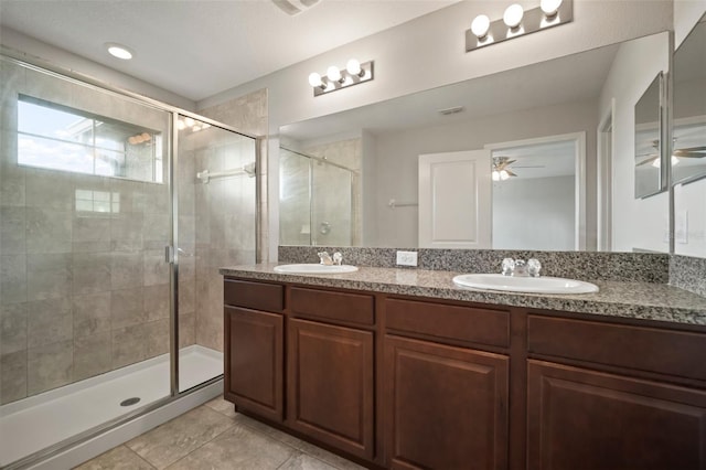 full bath with a sink, tile patterned flooring, double vanity, and a stall shower