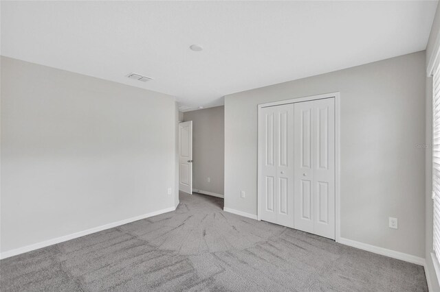 unfurnished bedroom featuring carpet floors, baseboards, a closet, and visible vents