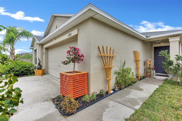 exterior space featuring an attached garage, roof with shingles, concrete driveway, and stucco siding