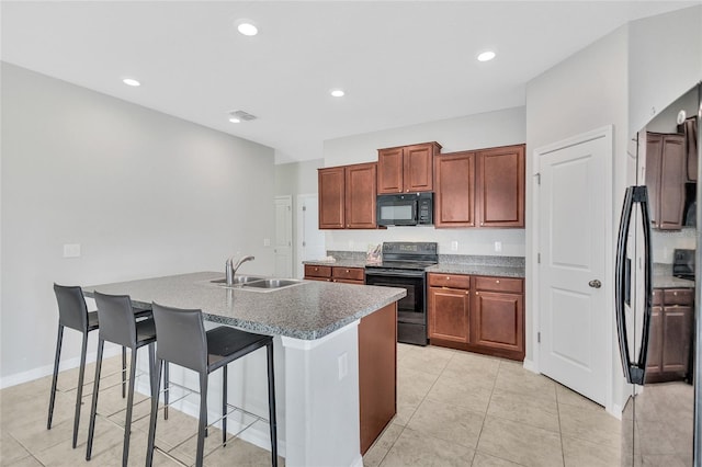 kitchen with a kitchen breakfast bar, recessed lighting, a center island with sink, visible vents, and black appliances