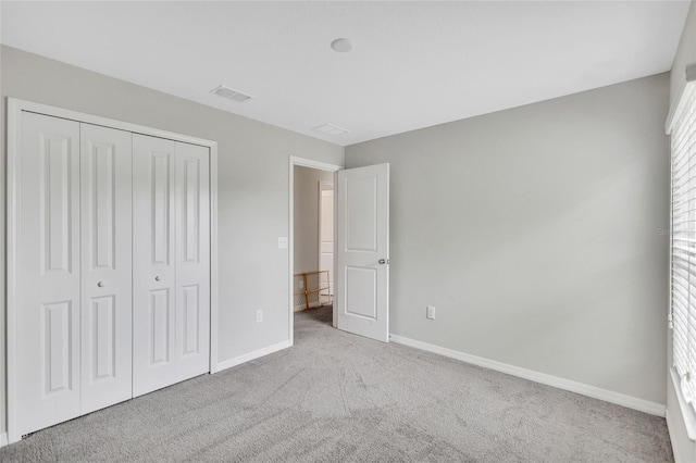 unfurnished bedroom featuring a closet, carpet flooring, visible vents, and baseboards