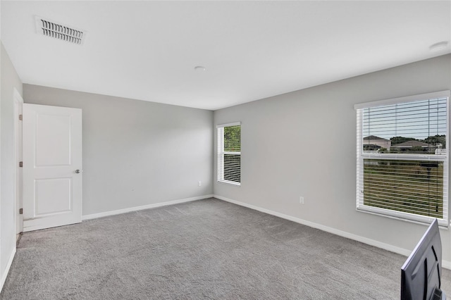 carpeted spare room featuring visible vents and baseboards