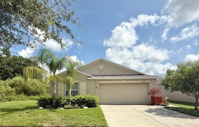 10936 Rainbow Pyrite Dr, Wimauma, FL 33598 - view of front of house featuring an attached garage, stucco siding, driveway, and a front lawn