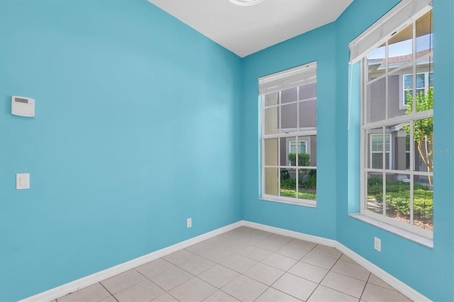 empty room with baseboards and light tile patterned floors