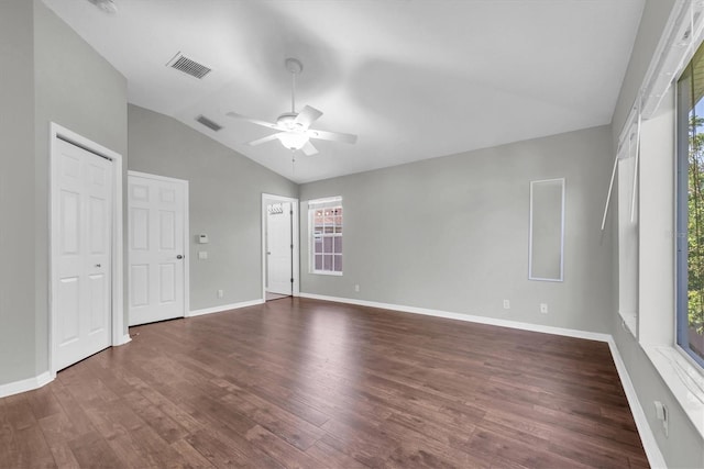 unfurnished bedroom with visible vents, dark wood-style floors, vaulted ceiling, and multiple windows