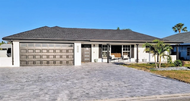 ranch-style house with roof with shingles, a garage, and decorative driveway