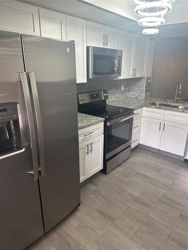 2275 62nd Ave N Unit 5202, Saint Petersburg, FL 33702 - kitchen with white cabinets, a notable chandelier, a sink, appliances with stainless steel finishes, and wood finished floors