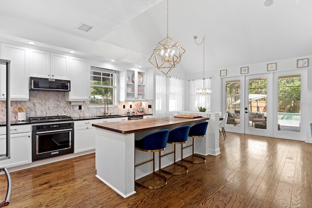 3325 W Wallcraft Ave, Tampa, FL 33611 - kitchen with oven, an inviting chandelier, a sink, butcher block counters, and white cabinetry