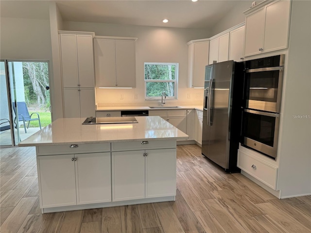 kitchen featuring a center island, white cabinets, a sink, appliances with stainless steel finishes, and recessed lighting