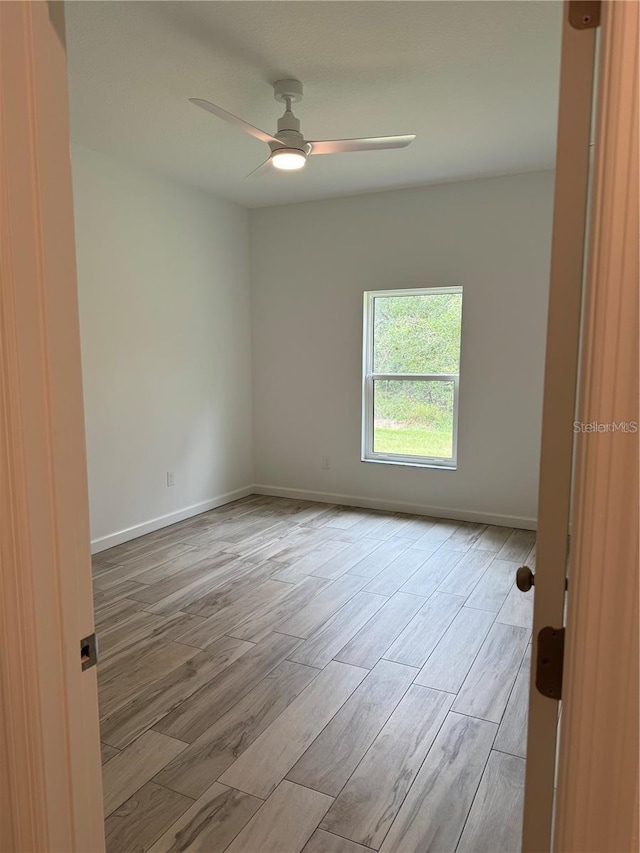 empty room featuring light wood-style flooring, ceiling fan, and baseboards