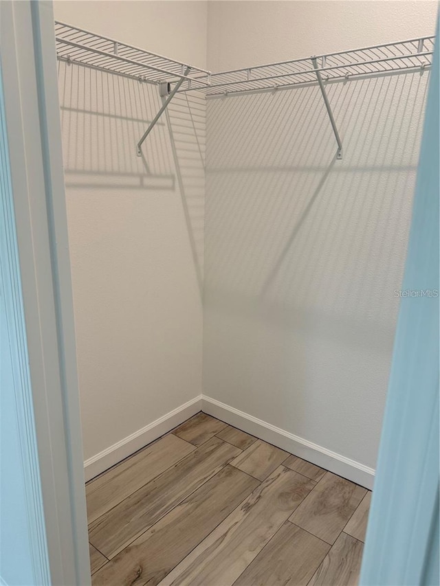 walk in closet with light wood-style floors