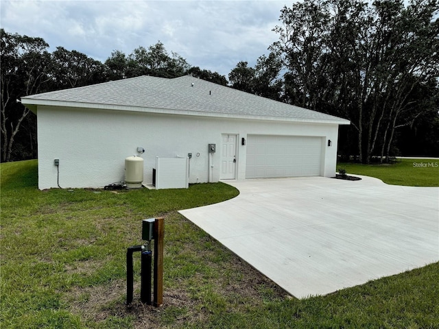 view of side of home featuring a garage, a lawn, concrete driveway, stucco siding, and roof with shingles