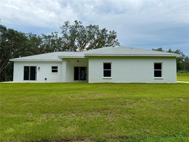 back of property featuring a yard, roof with shingles, a ceiling fan, and stucco siding