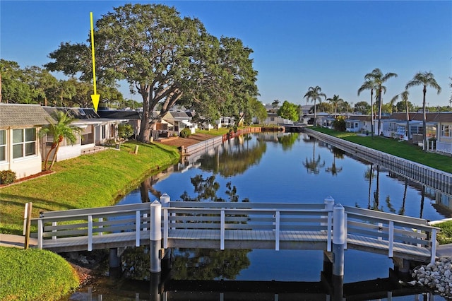 view of dock featuring a water view, a yard, and a residential view