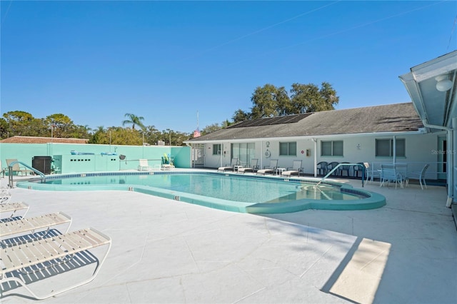 pool with a patio area and fence