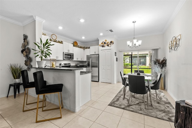 36519 Garden Wall Way, Zephyrhills, FL 33541 - kitchen with stainless steel appliances, a peninsula, a chandelier, ornamental molding, and white cabinetry