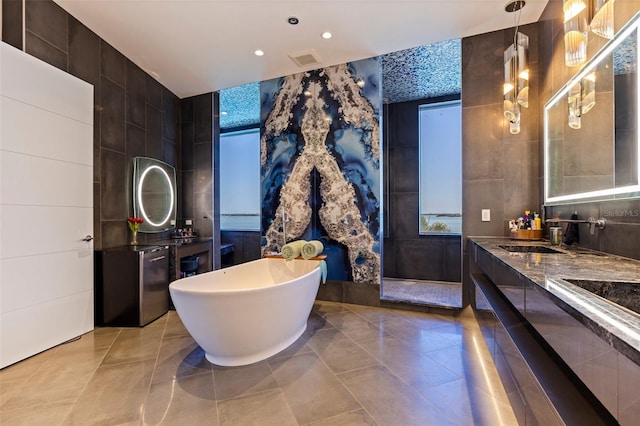 12650 7th St E, Treasure Island, FL 33706 - full bathroom with double vanity, a sink, a soaking tub, tile patterned floors, and tile walls