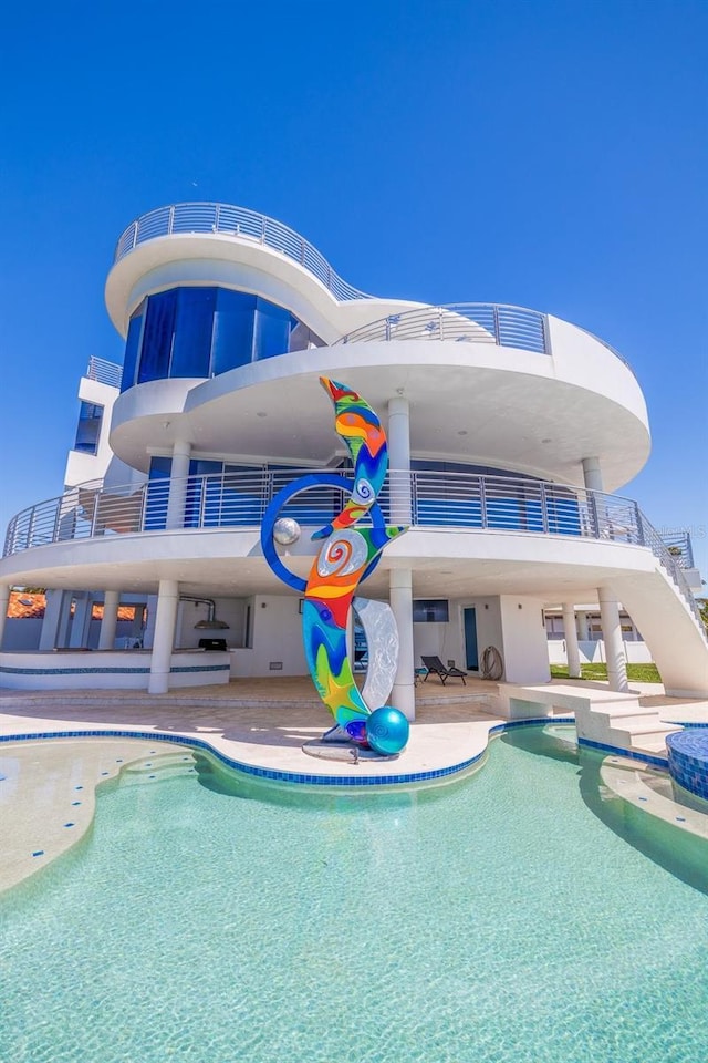 12650 7th St E, Treasure Island, FL 33706 - back of property featuring a patio, an outdoor pool, and a balcony