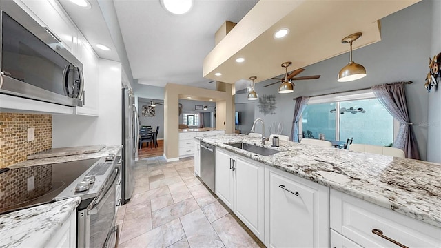 1613 E Del Webb Blvd, Sun City Center, FL 33573 - kitchen featuring appliances with stainless steel finishes, a sink, ceiling fan, backsplash, and white cabinetry