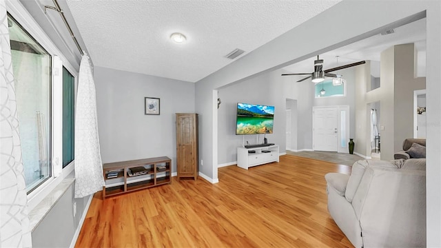 1613 E Del Webb Blvd, Sun City Center, FL 33573 - living room with ceiling fan, a textured ceiling, light wood-style flooring, and baseboards
