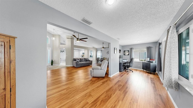1613 E Del Webb Blvd, Sun City Center, FL 33573 - living room with an office area, light wood finished floors, ceiling fan, a textured ceiling, and baseboards