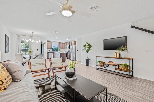 5429 Companion Ln, Tampa, FL 33619 - living area with visible vents, light wood finished floors, baseboards, and ceiling fan with notable chandelier