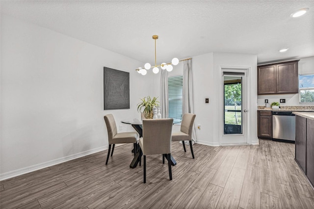 5429 Companion Ln, Tampa, FL 33619 - dining space with light wood-style flooring, a textured ceiling, baseboards, and a notable chandelier