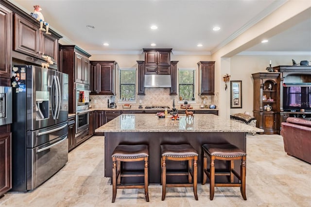 1509 Amarone Pl, Lutz, FL 33548 - kitchen with stainless steel appliances, under cabinet range hood, a breakfast bar area, light stone counters, and backsplash