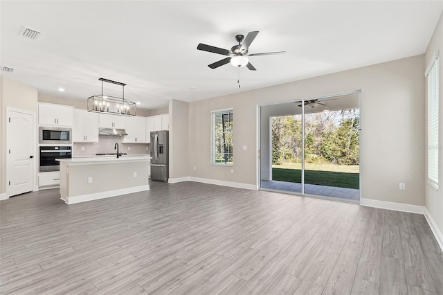 unfurnished living room featuring light wood-style flooring, baseboards, a ceiling fan, and visible vents