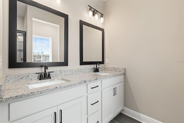 bathroom with a sink, baseboards, and double vanity
