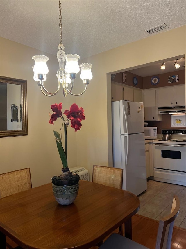 dining area featuring an inviting chandelier, a textured ceiling, and visible vents
