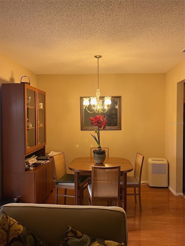 dining area with a chandelier, visible vents, a textured ceiling, and wood finished floors