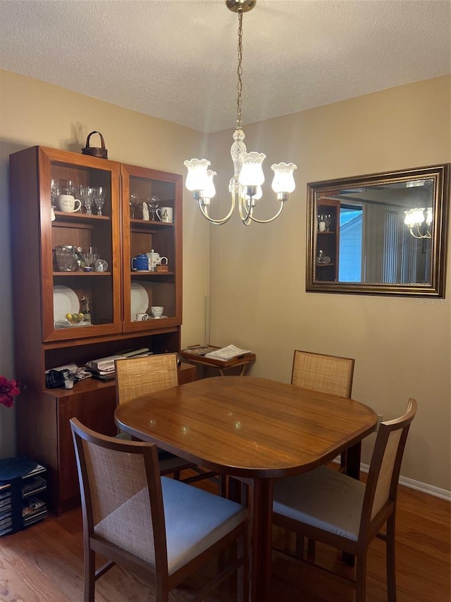 dining space with a chandelier, a textured ceiling, and wood finished floors