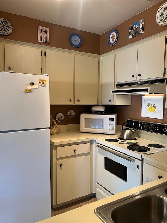 kitchen with under cabinet range hood, white appliances, light countertops, and white cabinets
