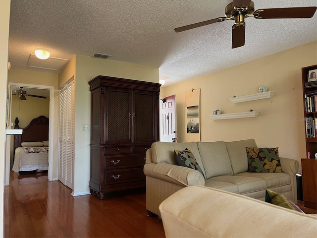 living area with a textured ceiling, visible vents, dark wood-style flooring, and a ceiling fan