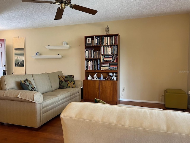 living room with a textured ceiling, wood finished floors, baseboards, and ceiling fan