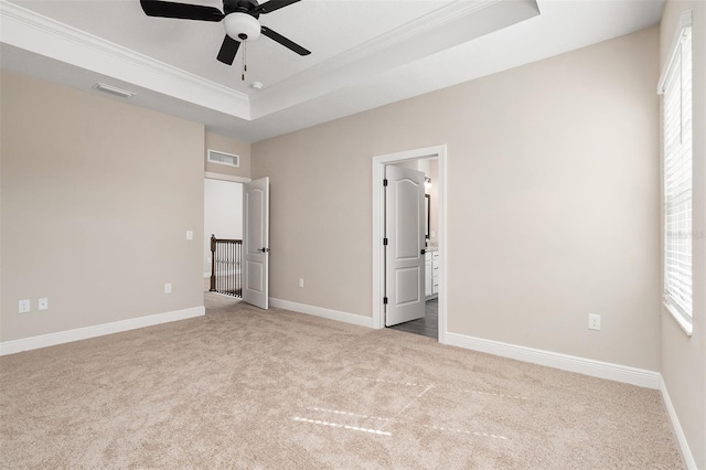 unfurnished bedroom featuring a raised ceiling, visible vents, ornamental molding, and carpet
