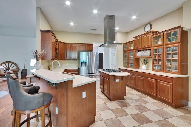 16420 Iola Woods Trl, Dade City, FL 33523 - kitchen with island exhaust hood, a peninsula, light countertops, brown cabinetry, and stainless steel appliances