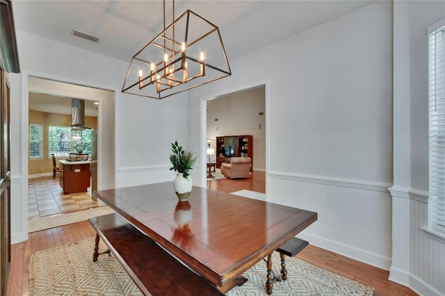 16420 Iola Woods Trl, Dade City, FL 33523 - dining area with a chandelier, light wood finished floors, visible vents, and a wainscoted wall